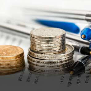 stack of coins on top of financial documents with a pen
